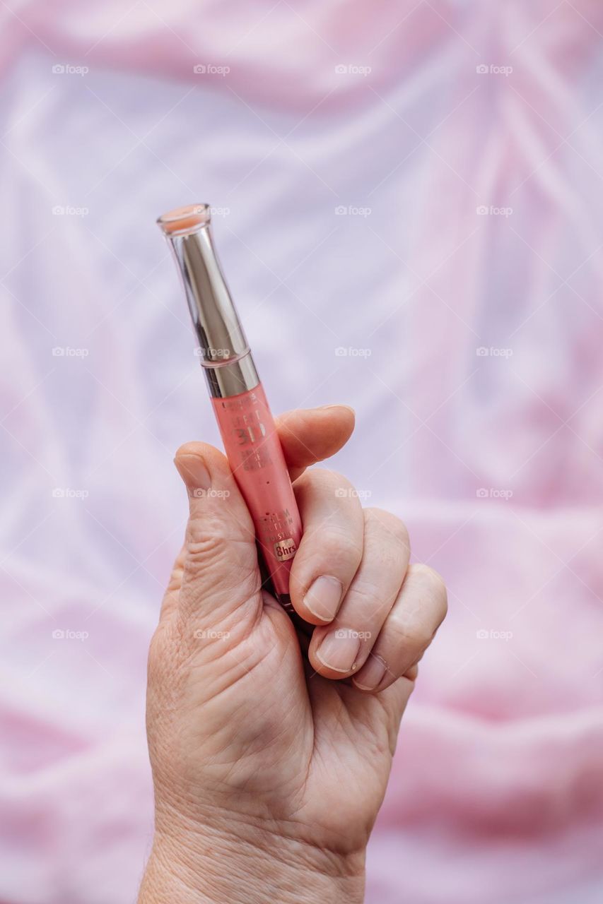 lip gloss in hand of person