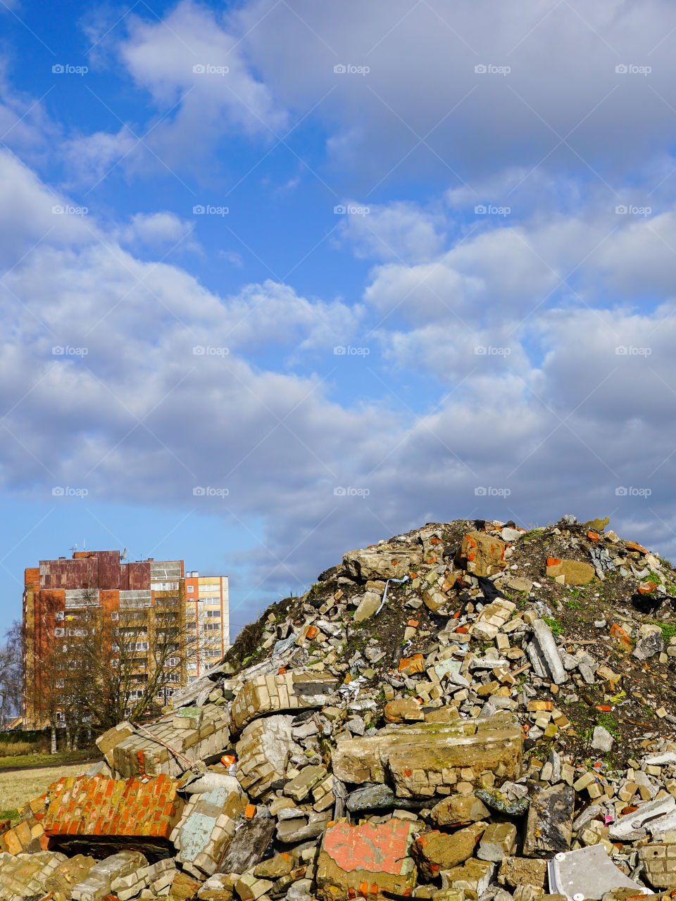 heap of rubble after demolition of an old house, suburban block of flats background