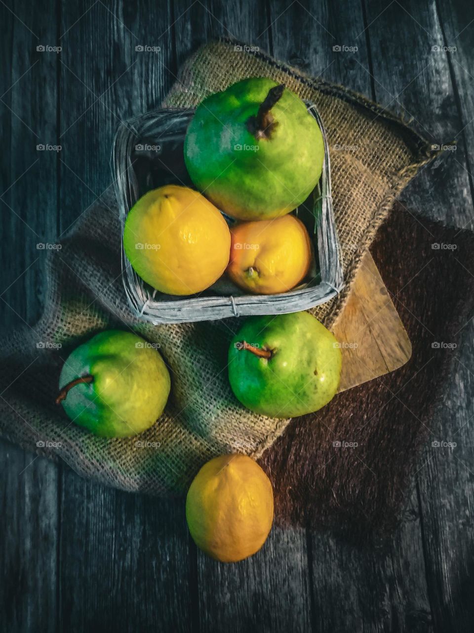 Lemon and green pears in a basket and on the table top