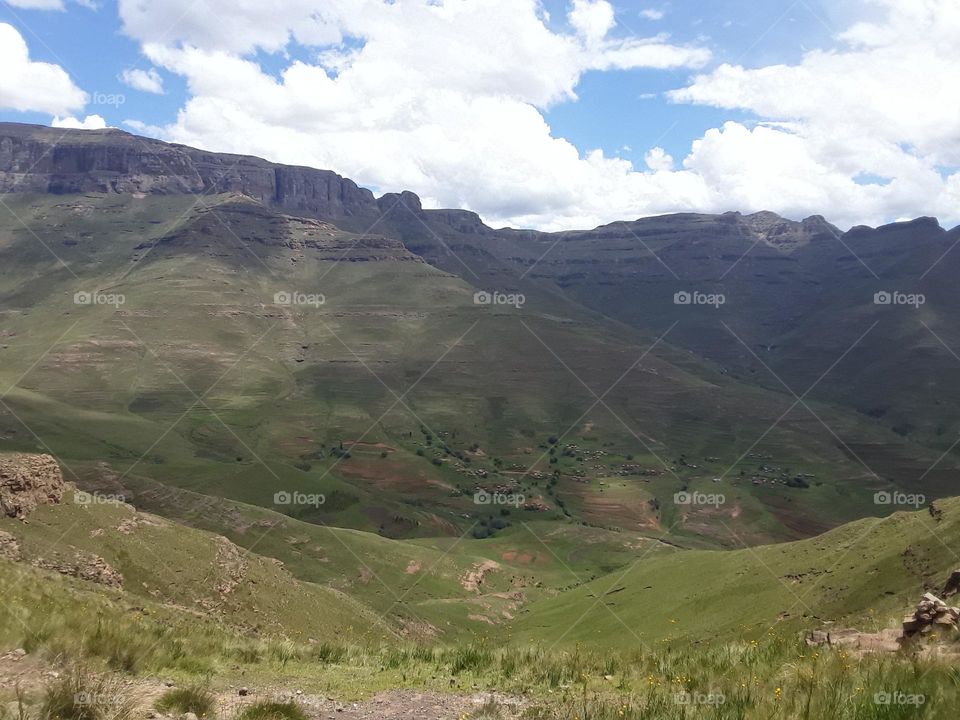 A display of a landscape from the distance with cloudy skies at summertime.