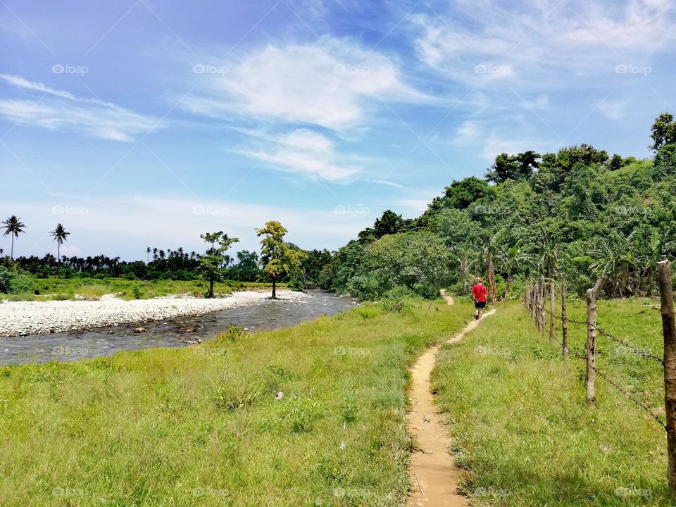 Hiking along a river surrounded by tropical rainforest and exotic landscape in Abra de Ilog, Mindoro, Island of Philippines