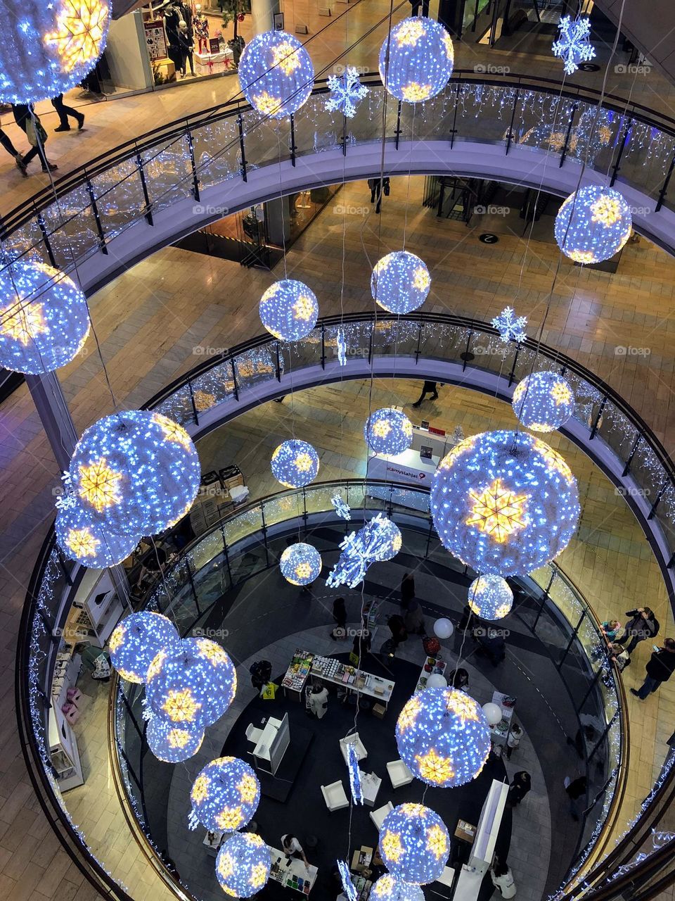 Beautiful seasonal decorations in the shopping mall through  the floors, blue shiny lighted spheres with yellow snowflakes 