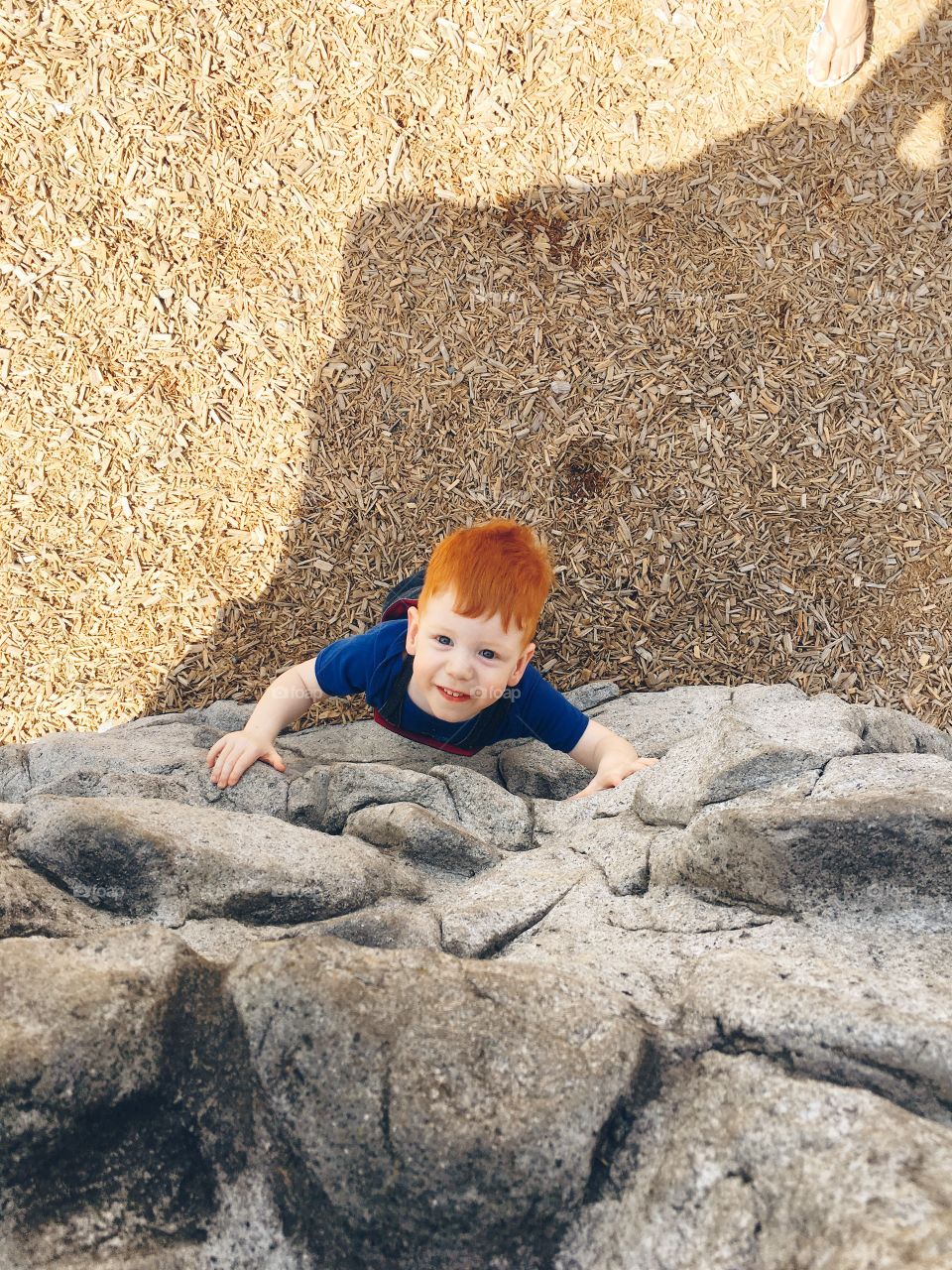 Toddler climbing the rocks at the playground 