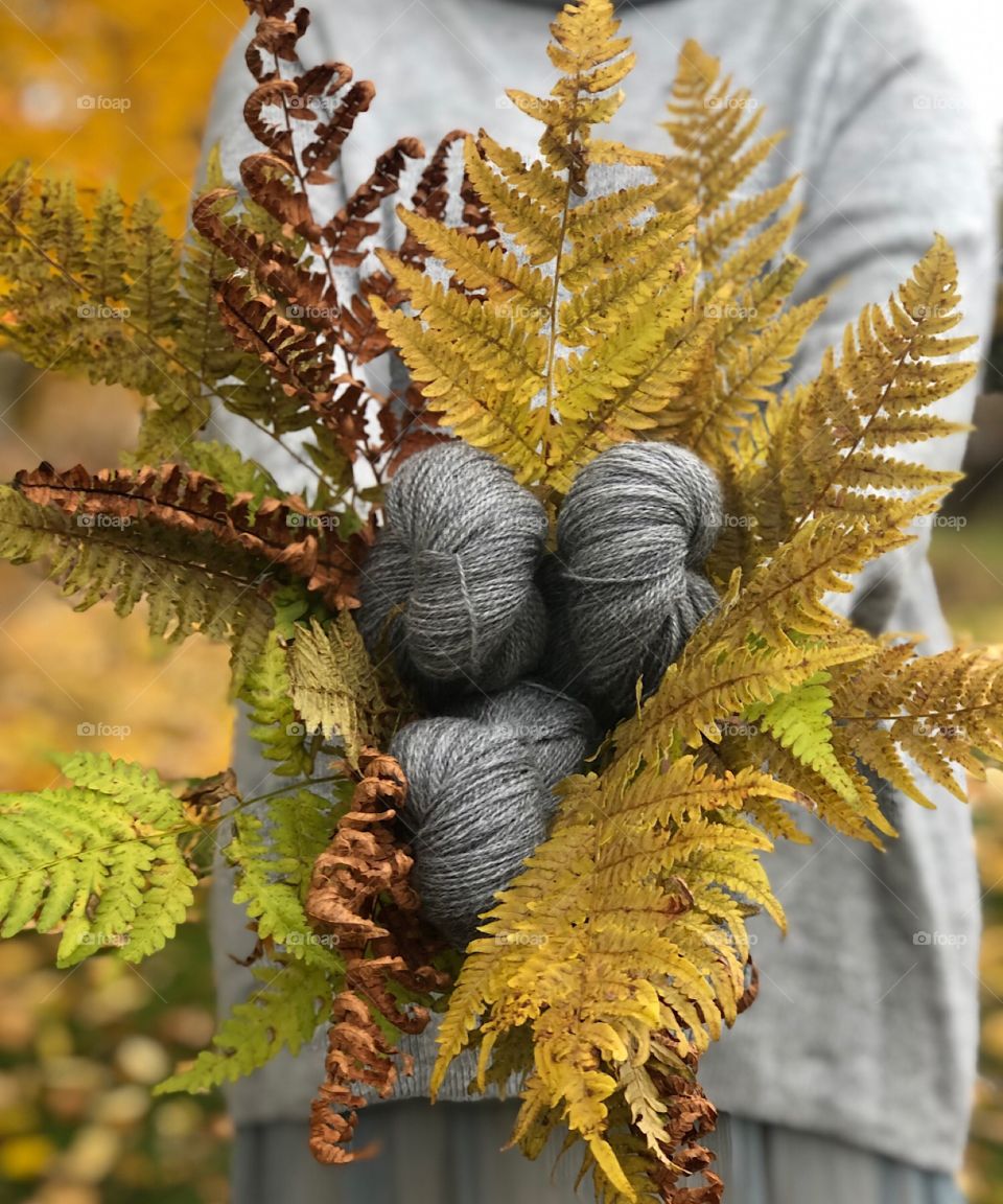 Holding yarns and autumn leafs. Shades of yellow and grey. 