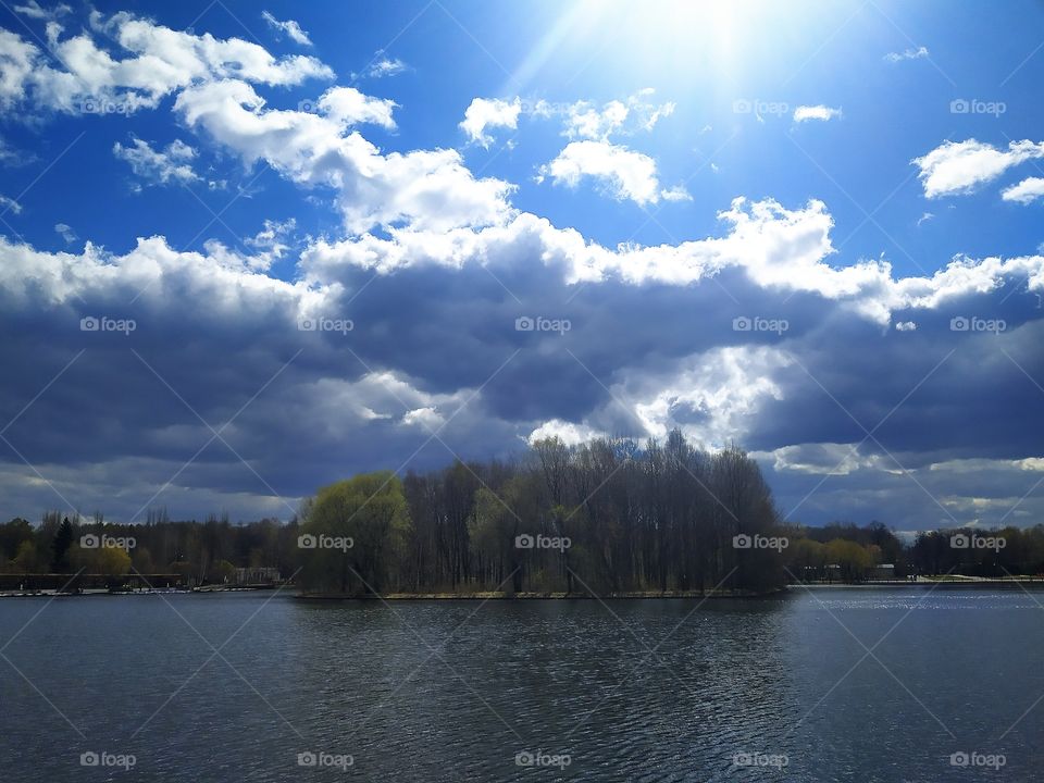 River, forest, blue sky with clouds and sun rays