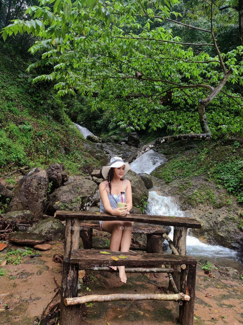 Portrait of woman sitting against waterfall