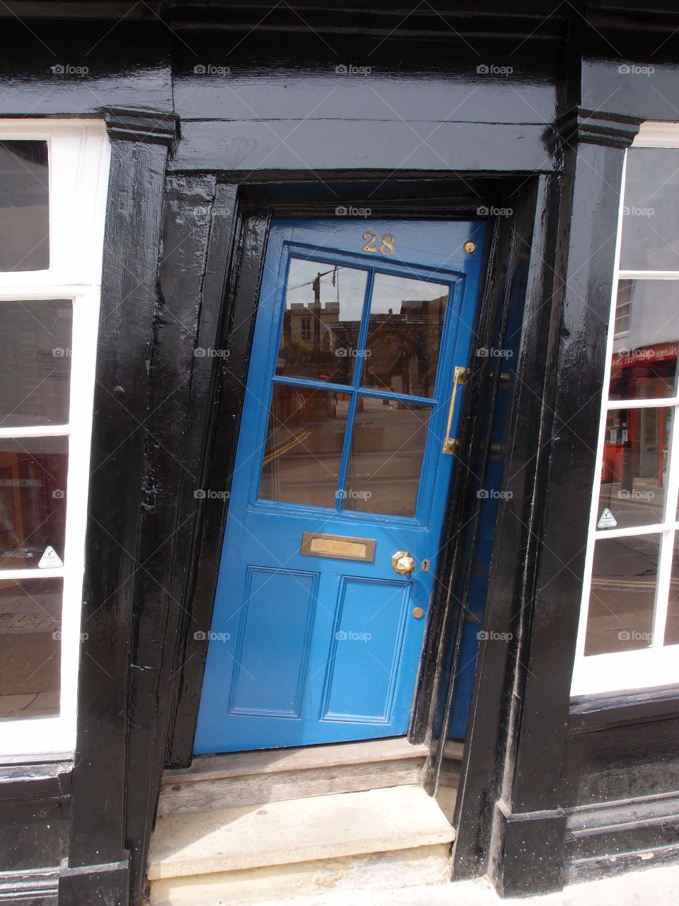 A unique slanted blue door in a black building in England on a summer day. 