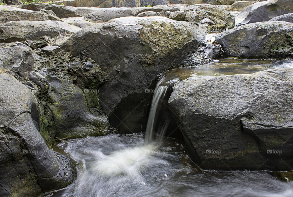 The water flowing over rocks and trees down a waterfall at Khao Ito waterfall , Prachin Buri in Thailand.