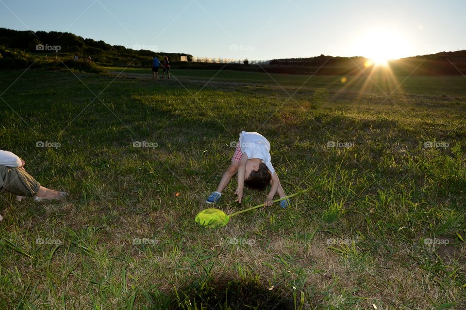 boy playing in the field during the sunset