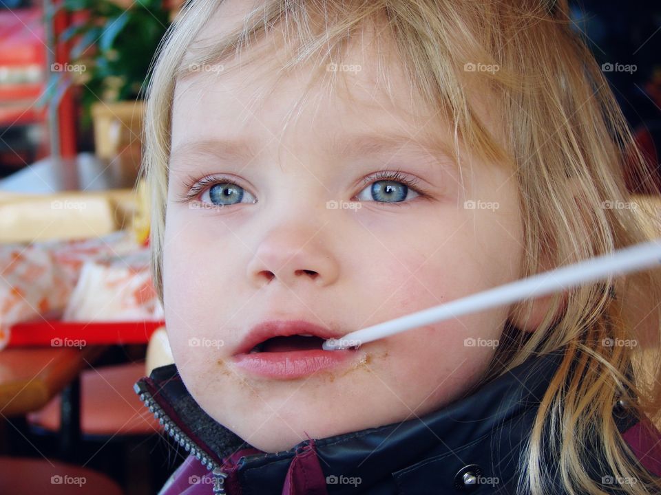 At the restaurant. Girl in her own thoughts with drinking straw in her mouth