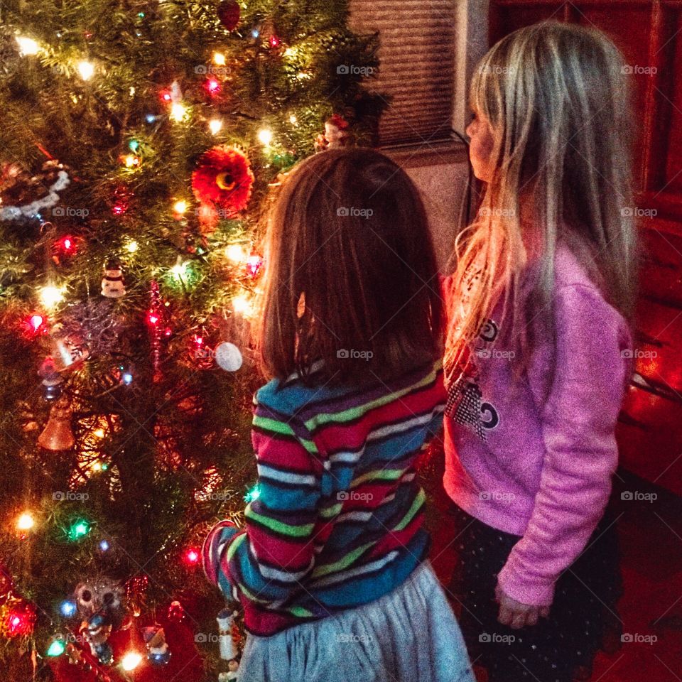 Sisters admiring their Christmas tree decorating. 