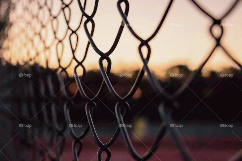 Close-up view of fence netting with beautiful sunset background. This is a very artistic and interesting photo