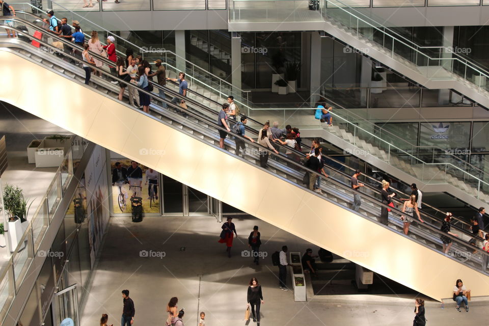 a view of people on escalators in an open air shopping and business center in Paris.