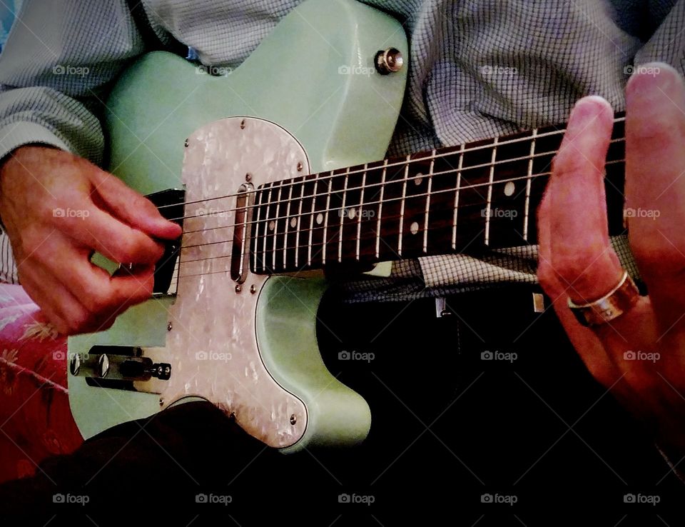 Man's Hand Playing Telecaster Style Guitar in Surf Green with Pearloid Pick Guard