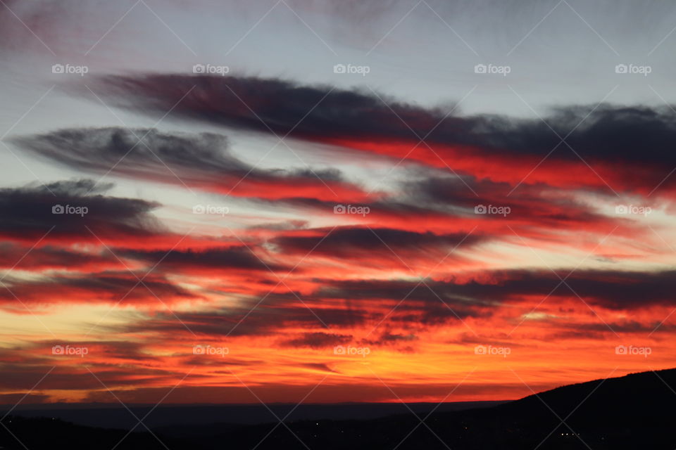 Blue and grey sky with dark grey, bright red and orange clouds