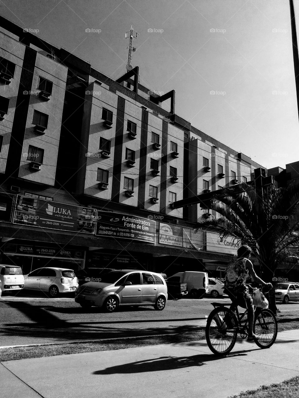 mundo moderno em preto e branco. Homem montado em bicicleta e carros ao fundo.