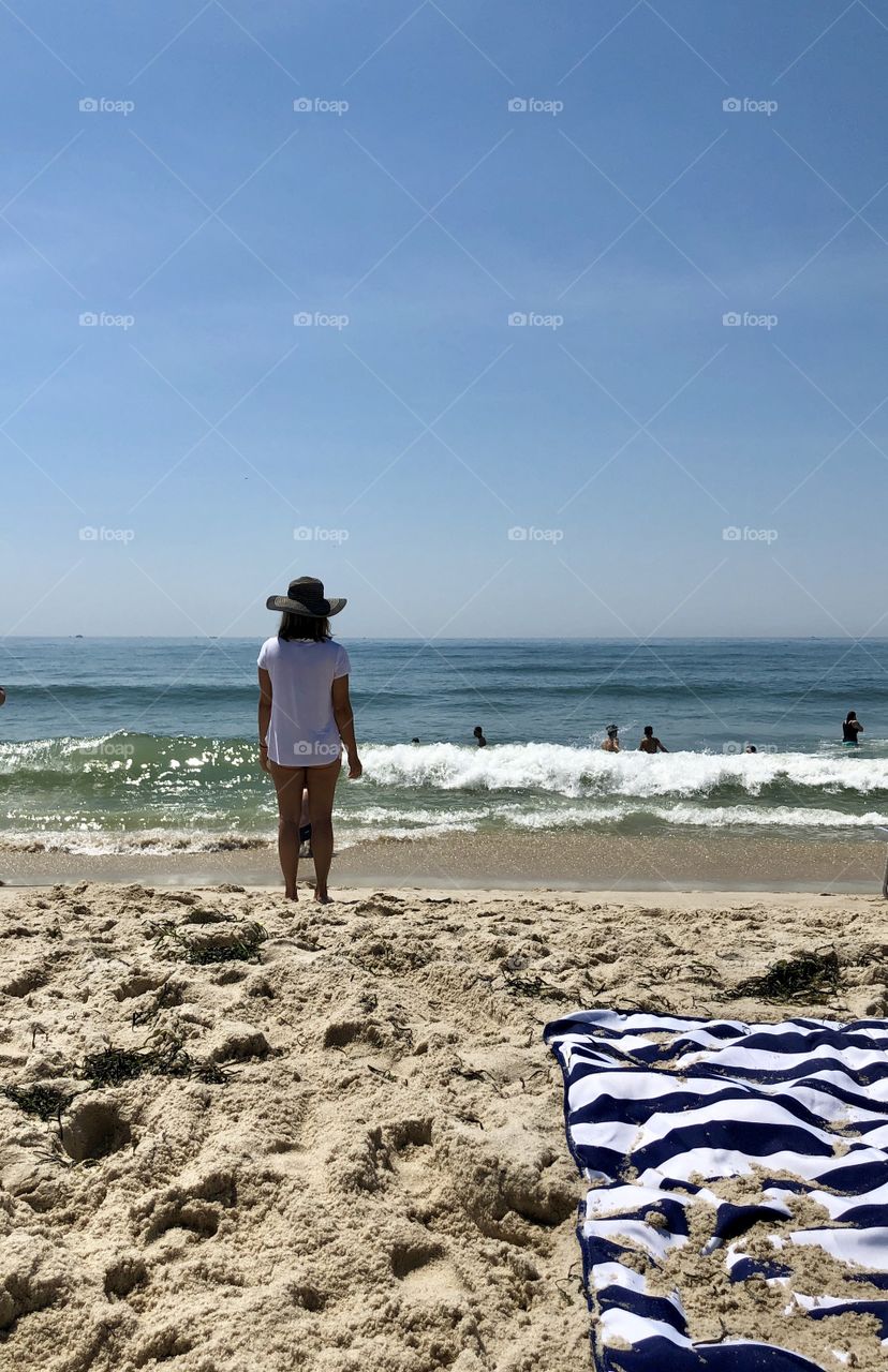 Woman with hat looking out to ocean