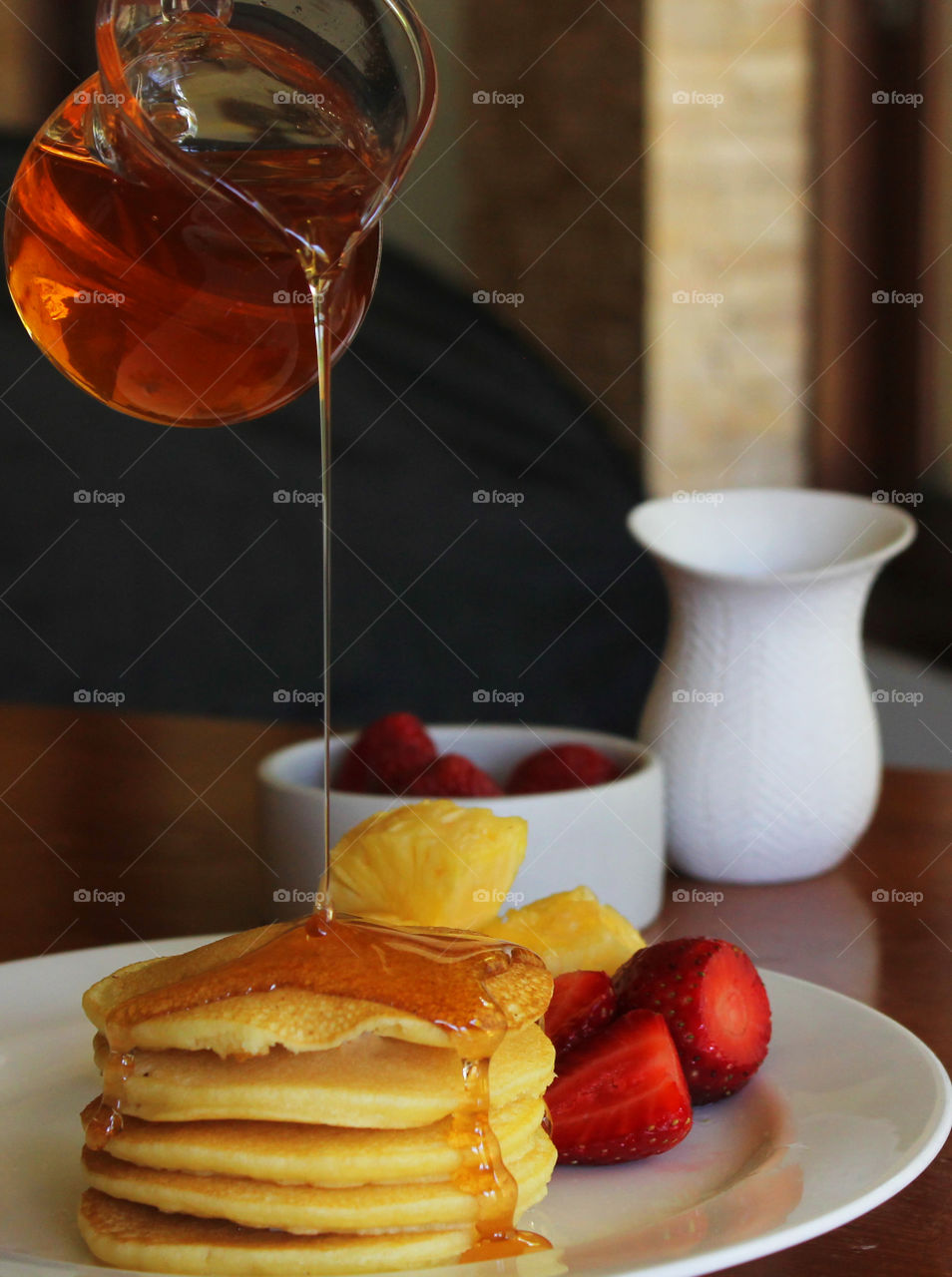 pouring maple syrup on pancake