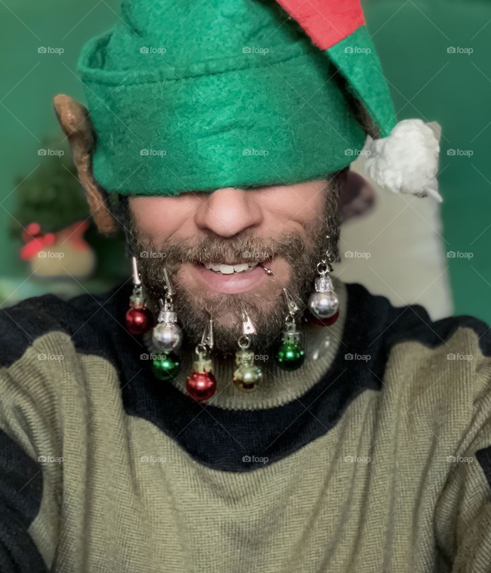 Man with baubles on his beard and wearing an elf hat 