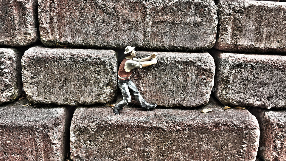 Old figurine toy on bricks . Found this guy figurine on top of small pyramid of bricks during a garden walk. 