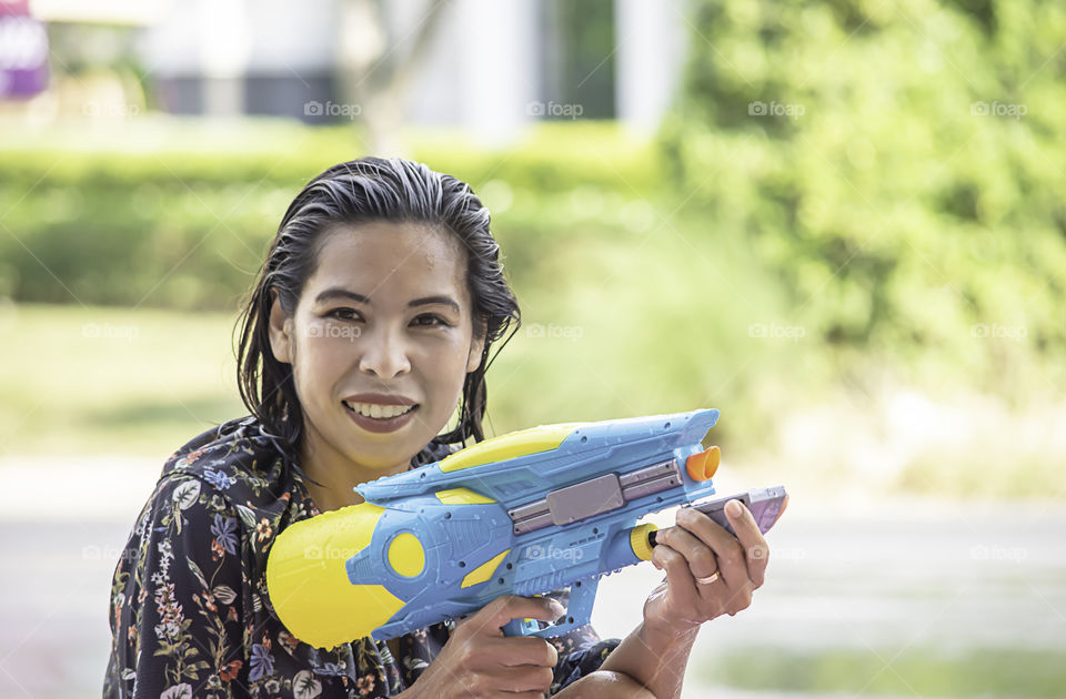 Asian woman holding a water gun play Songkran festival or Thai new year in Thailand.