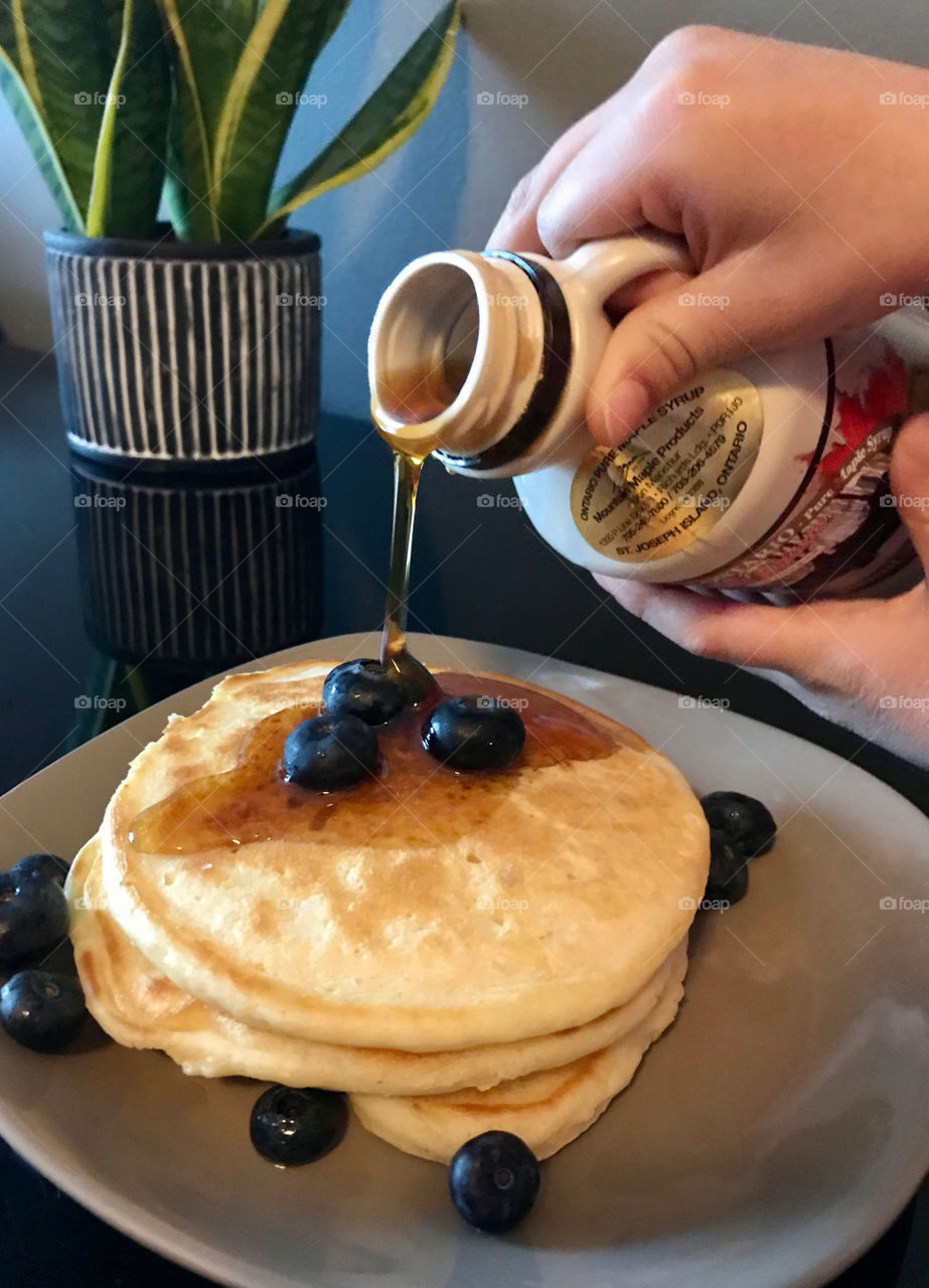 Maple syrup on pancakes with blueberries