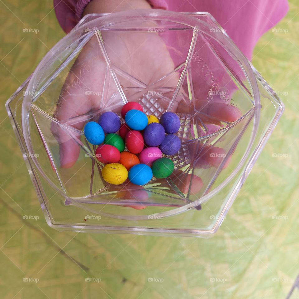 Colorful candies in plastic bowl on palm