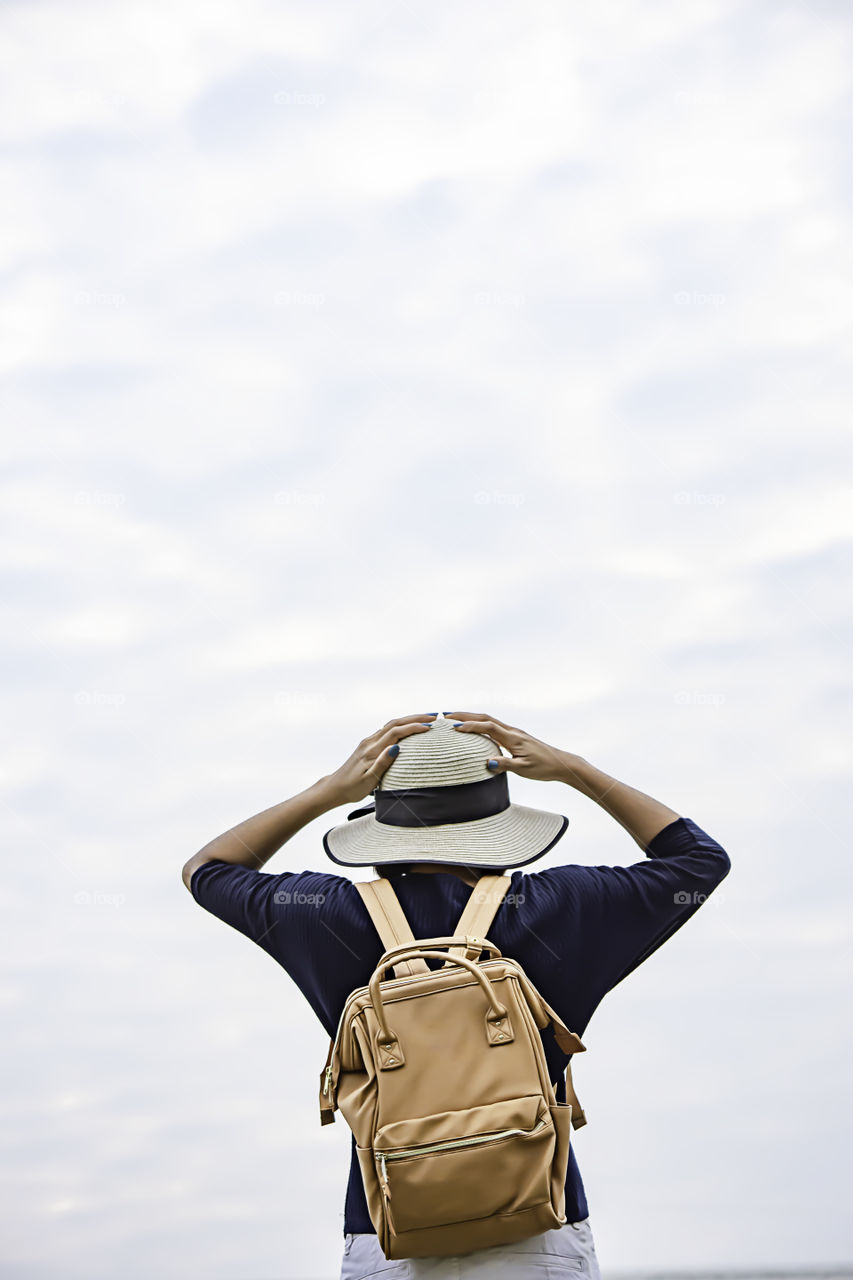 Women shoulder backpack and Wear a hat Background sky.