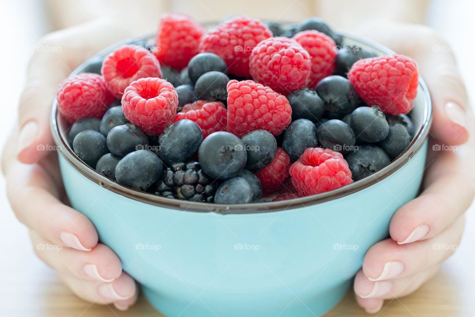 Summer healthy snack in hands, fresh berries in a bowl