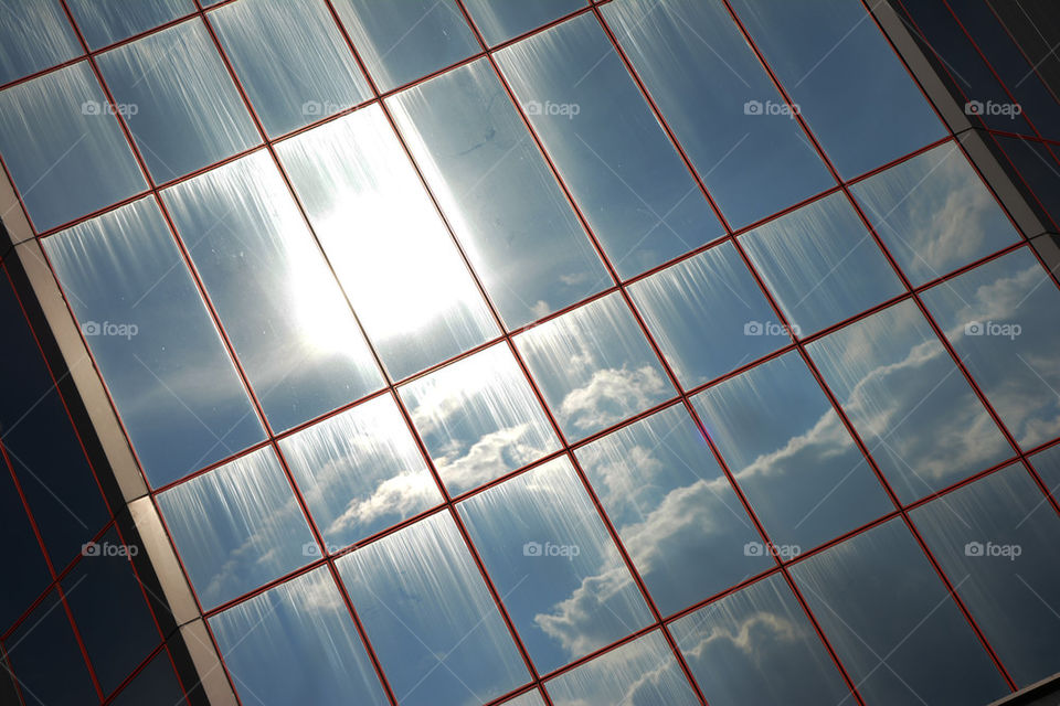 reflection of sun and skies in glass building