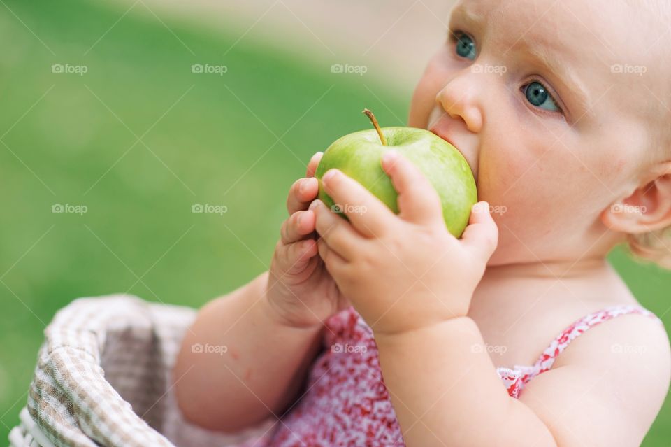 Cute little girl eating green apple