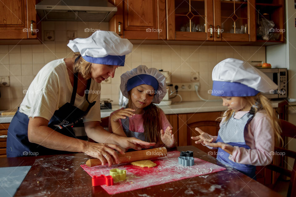 Little sisters with grandma cooking the biscuits 