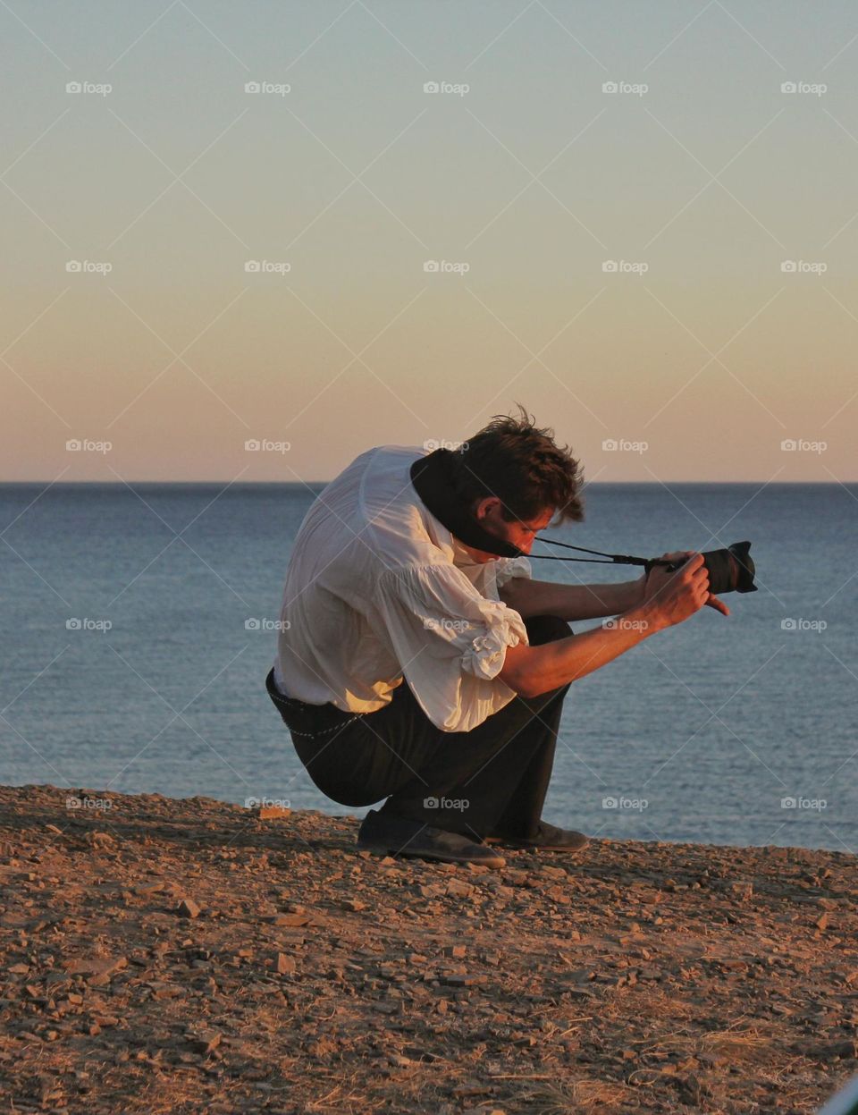 photographer sitting on the seashore takes a photo