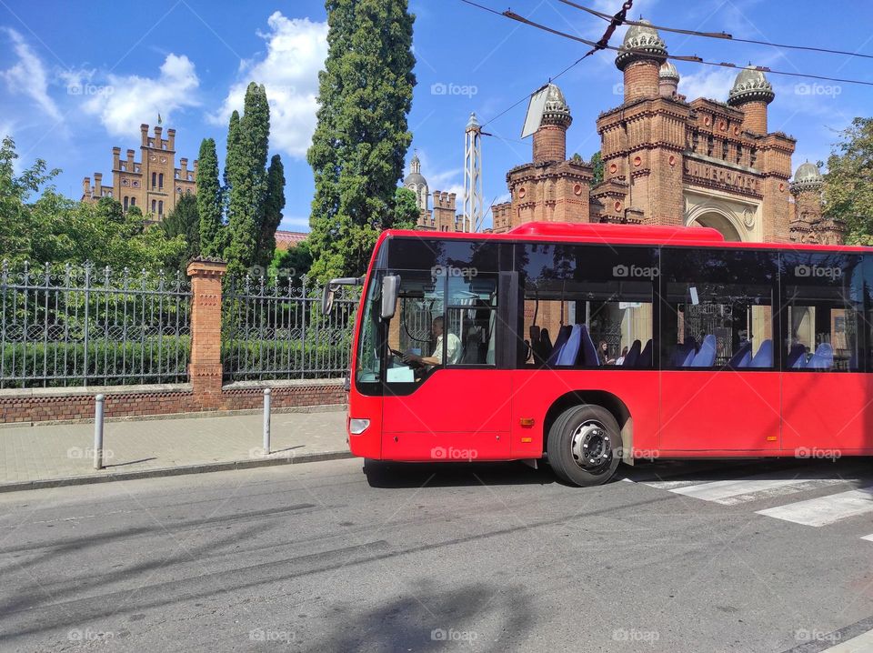 Red bus at the bus stop against the backdrop of the university