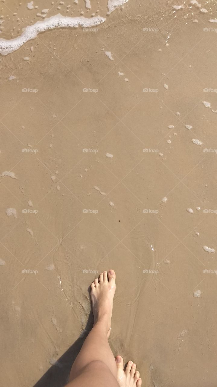 pés na areia fofa da praia com água transparente