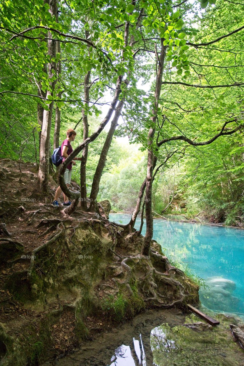 Woman looking at a lake surrounded by forest