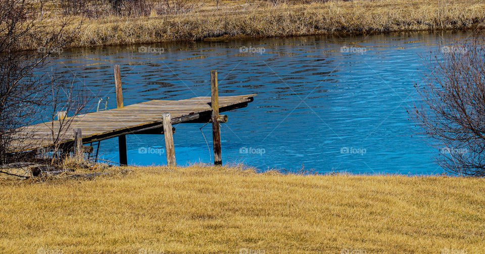 pond with a dock with ice on water