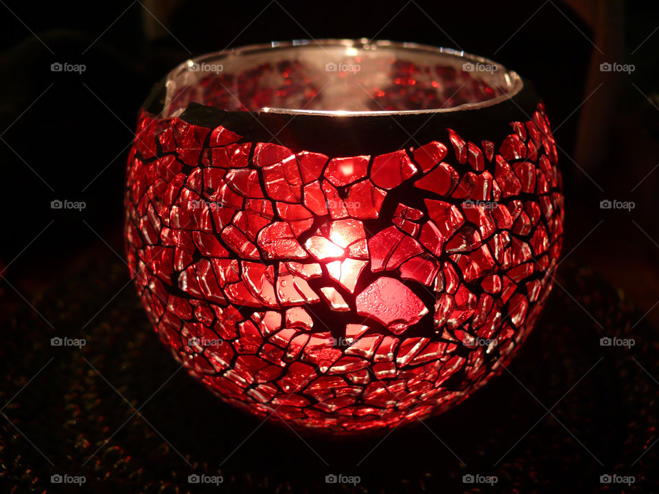 Close-up of lit candle light holder against dark background.