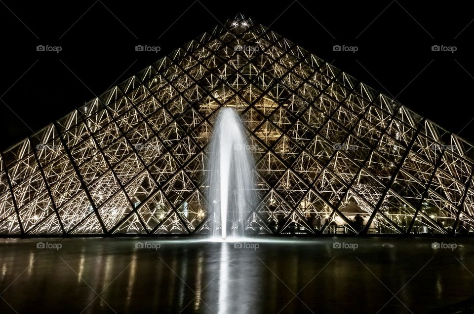 The triangular shape of Pyramide du Louvre points up into the night sky