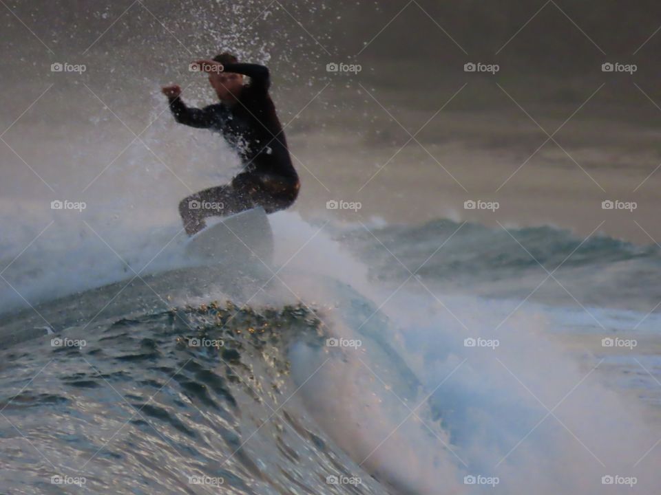 Summer by the ocean: action photo of surfer riding on top of the wave at sunset on the Australian coast.