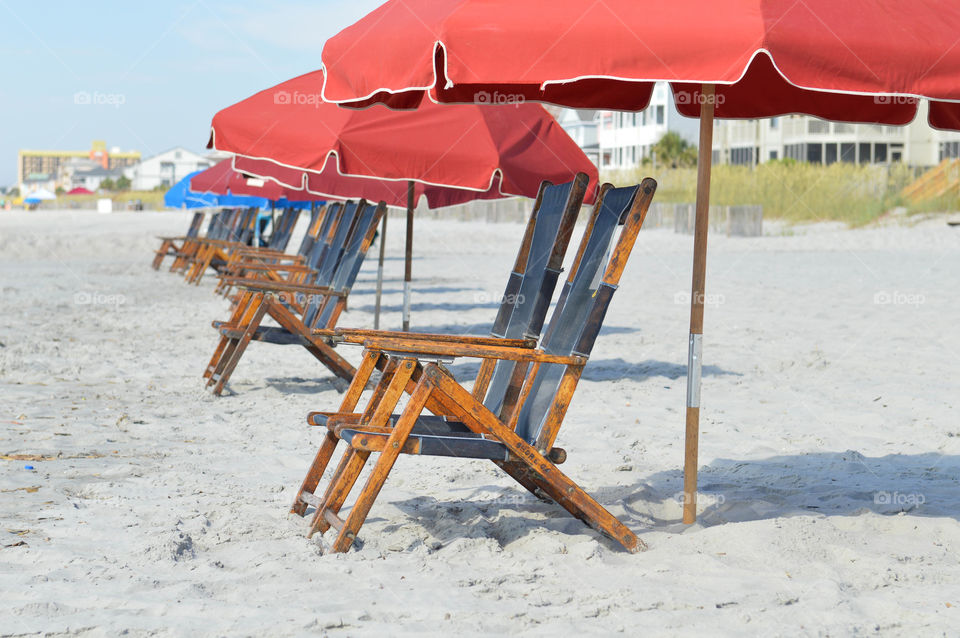 Row of lounge chairs and umbrellas set up on the beach with no people