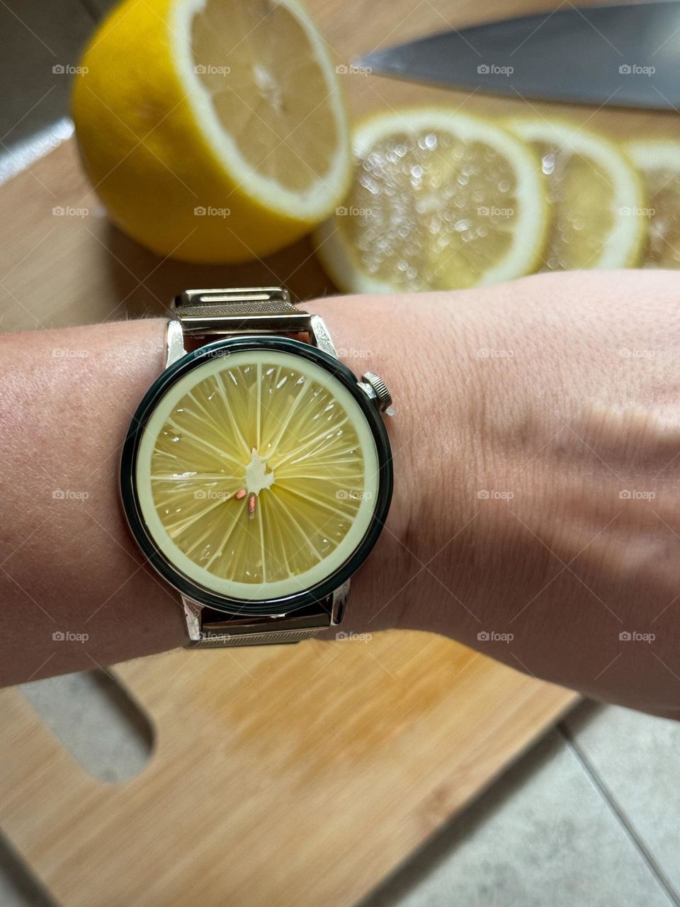 Lemon watch on hand on a background of sliced lemons 