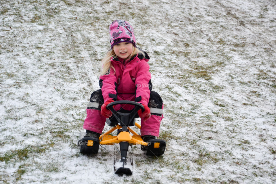 Young girl of five years old riding the sledge down a hill.