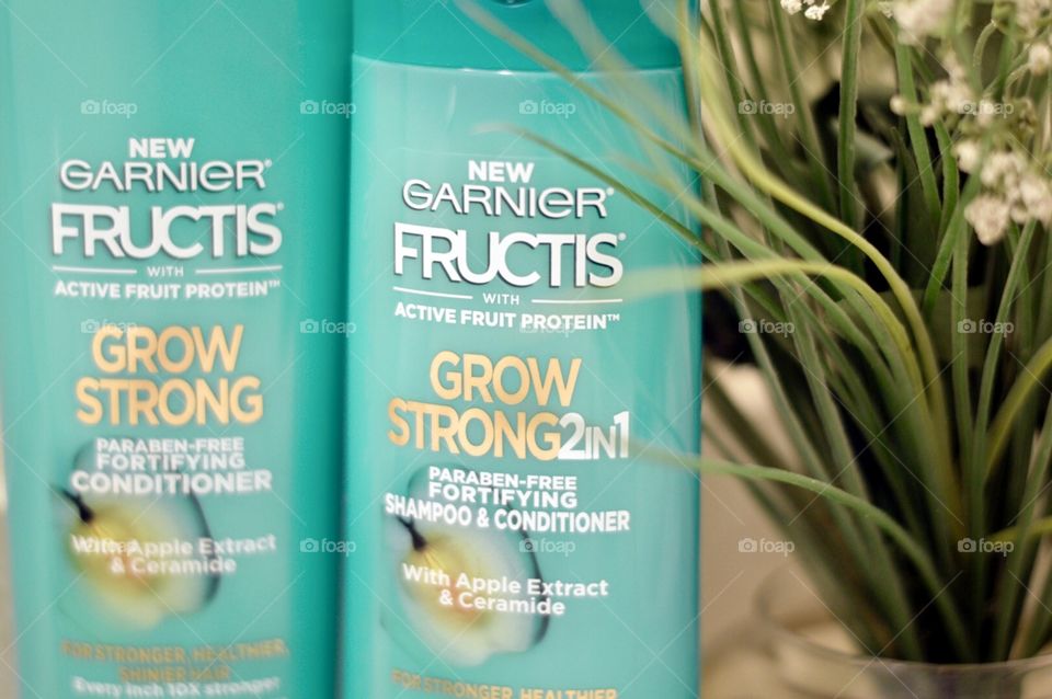 Garnier shampoo and conditioner on a bathroom countertop with a plant in the back room
