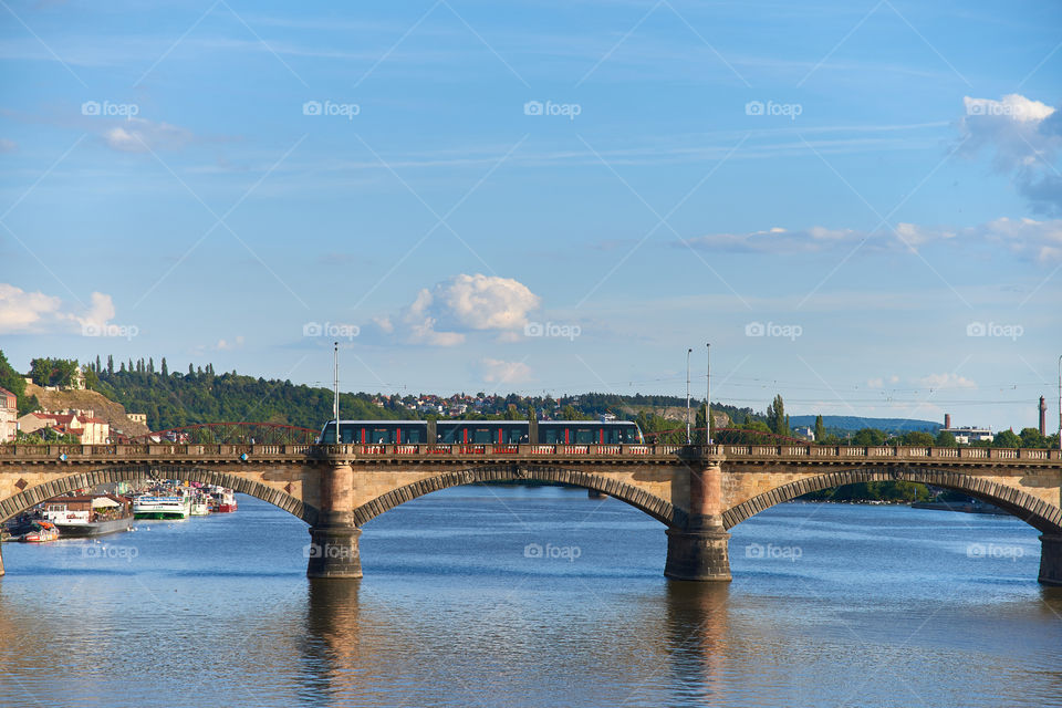 Prague, Czech Republic - July 3, 2017: Modern tram crossing bridge over Vltava river in Prague on sunny July evening.