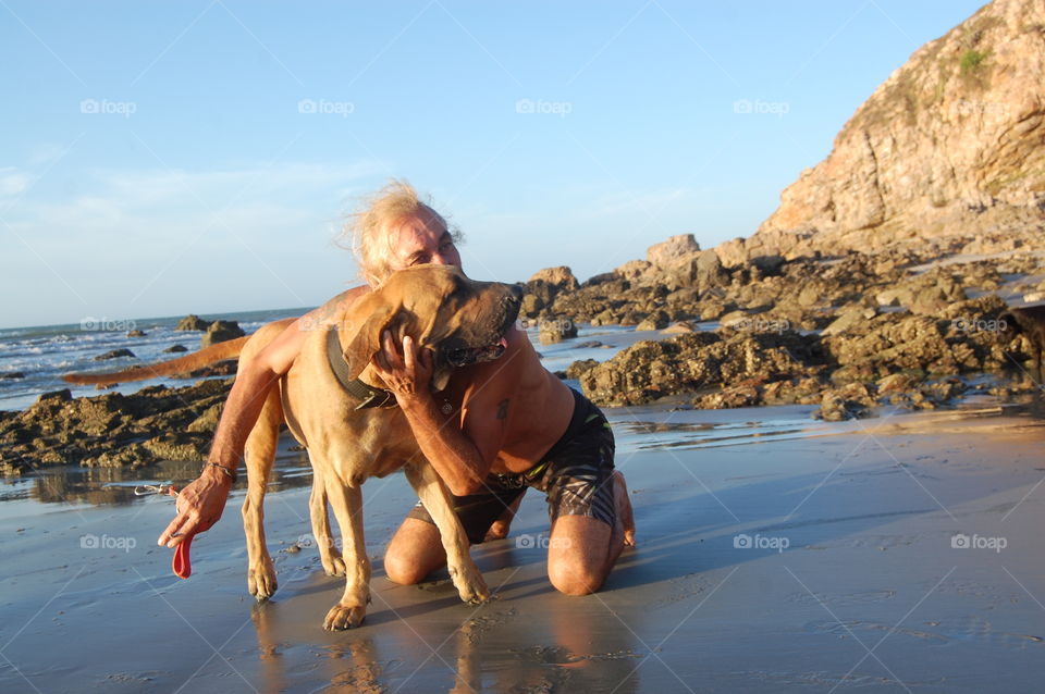 Man hugging his dog in the beach 