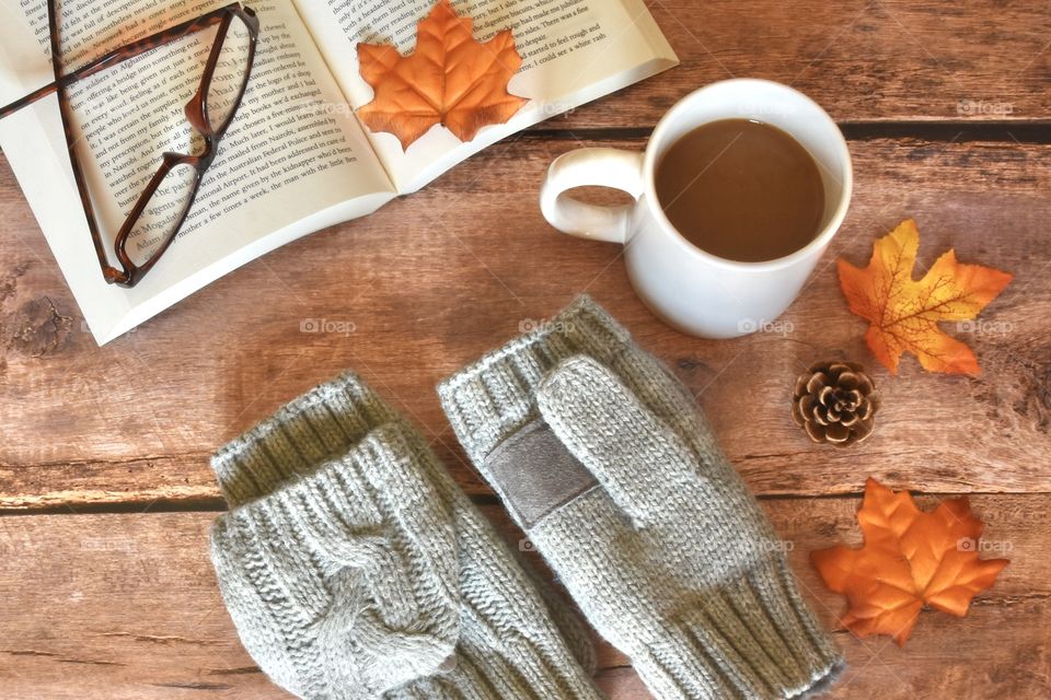 Sweater weather, gloves and hot chocolate book and glasses in a flat lay 