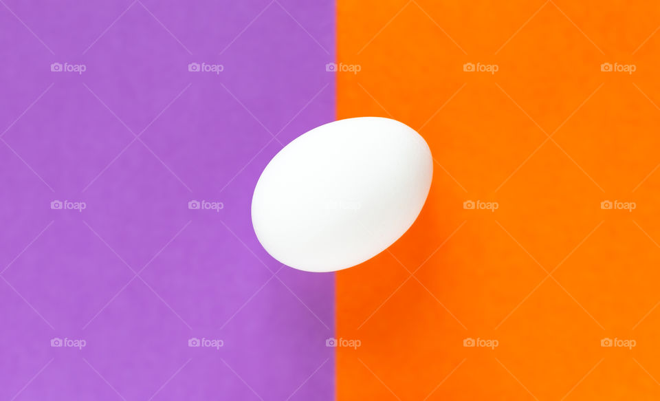 White egg on purple and orange background