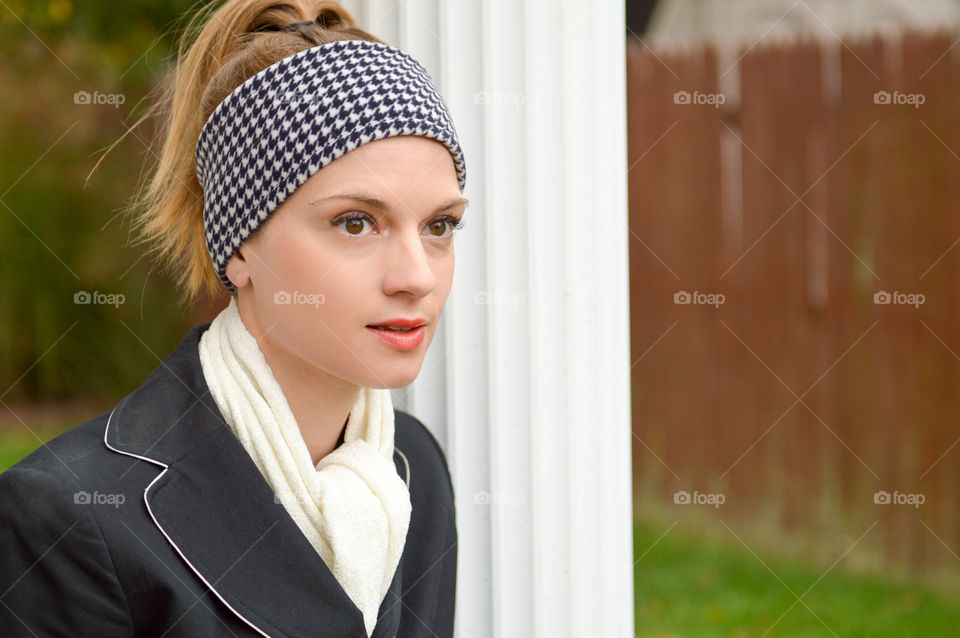 Woman wearing a fleece houndstooth headband and white scarf outside