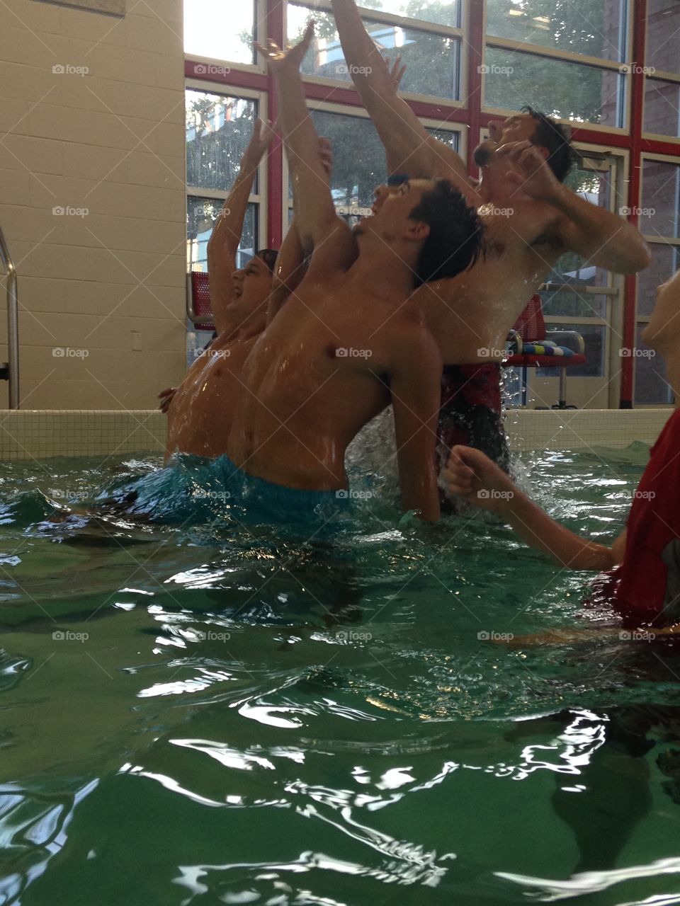 It's mine!. Boys jumping out of the water to catch a football 